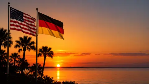 Amerikanische und deutsche Flagge vor einem Sonnenuntergang in Florida